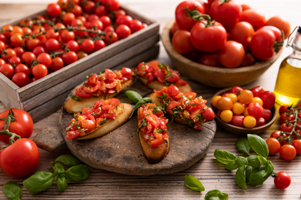 Bruschetta med tomater og basilikum, omgitt av ferske tomater i ulike farger