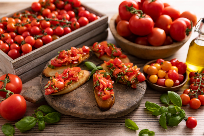 Bruschetta med tomater og basilikum, omgitt av ferske tomater i ulike farger