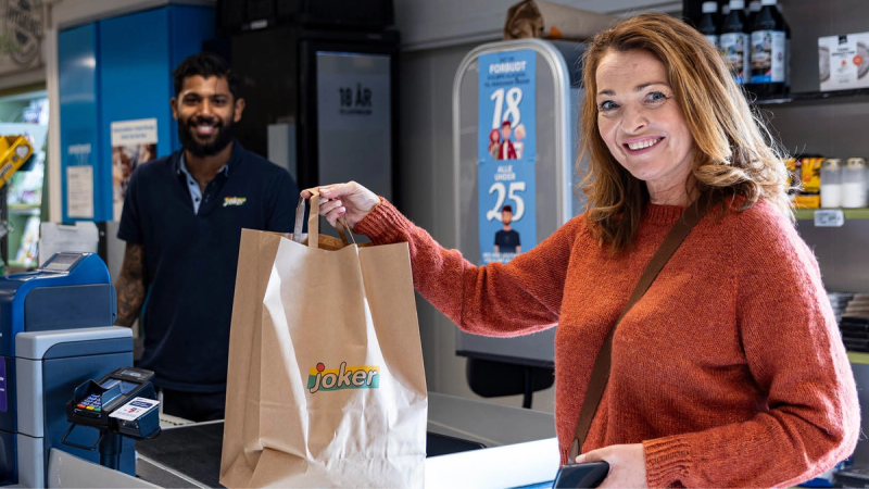 En kvinne handler på Joker og får med seg en handlepose fra kassen