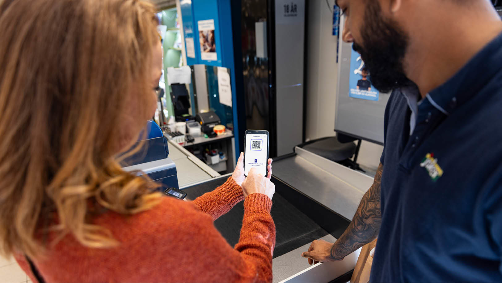 En kunde viser QR-kode på mobil i kassen hos Joker
