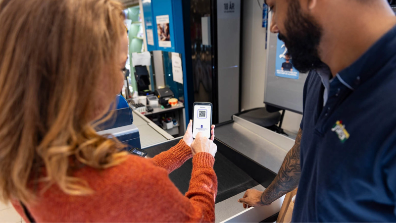 En kunde viser QR-kode på mobil i kassen hos Joker