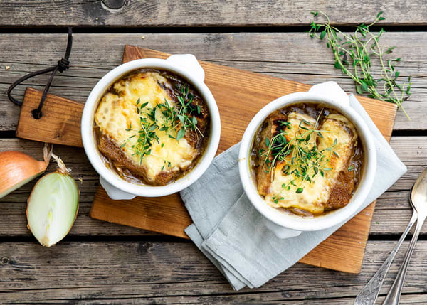 Løksuppe servert i ildfaste skåler med gratinert ost og fersk timian