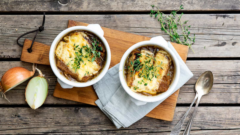 Løksuppe servert i ildfaste skåler med gratinert ost og fersk timian