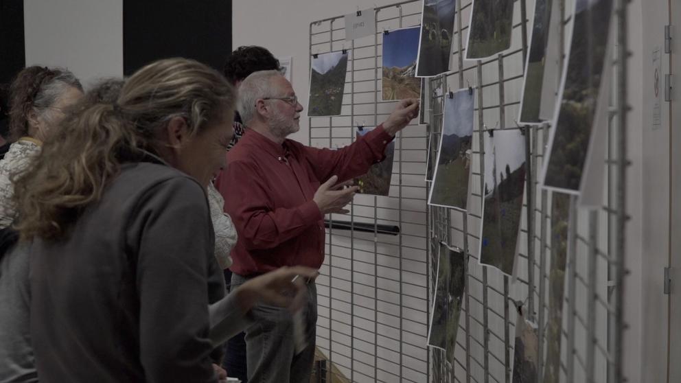 Les participants à l'atelier épinglant des photos de paysage sur un mur.