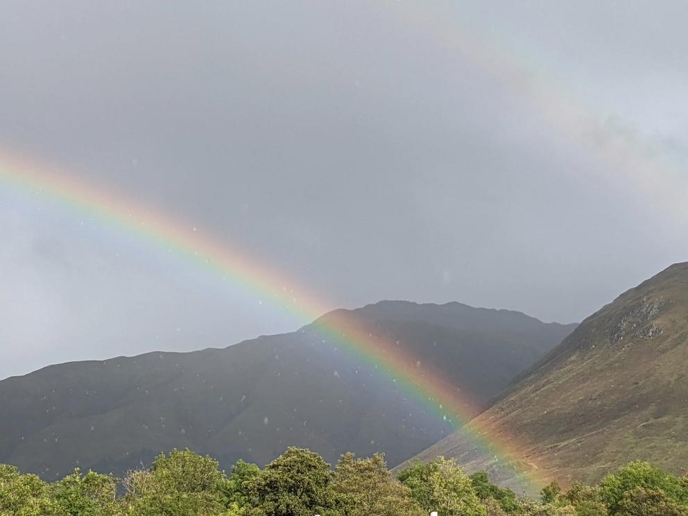 Image of Highland mountains intersected by a rainbow. 
