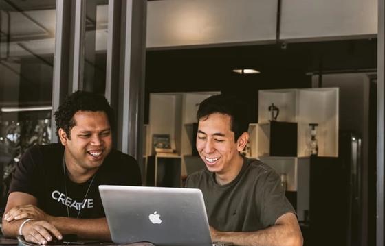 Two male employees working together in a startup office setting enviornment.