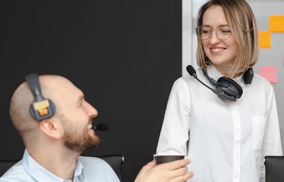 2 shift-based employees communicating effectively in a modern workplace, wearing headsets, emphasizing teamwork and connection in a shift-based work environment.