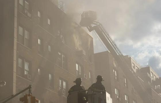 Firefighters using ladder trucks to manage a building fire, highlighting the need for real-time communication and firefighter morale during emergencies.