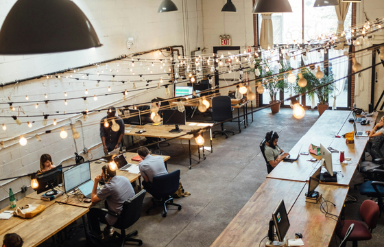 A modern coworking space with employees engaging in feedback loops, collaborating on organizational change, and enhancing workplace culture.