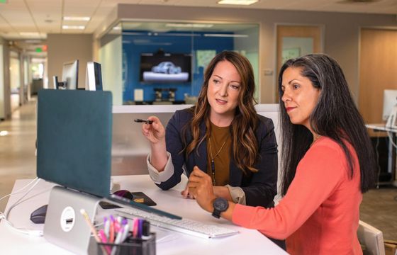 Two professionals discussing key leadership skills for workplace success in a modern office setting