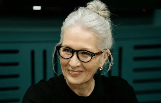 Smiling woman wearing glasses in a professional setting, embodying well-being and workplace positivity.