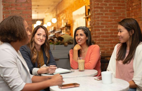 Diverse team of women having a casual business meeting in a cozy cafe setting.