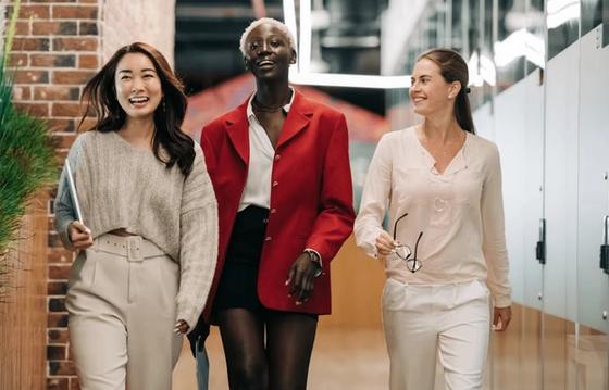 three diversified females who are walking down the hallway of an office studio.