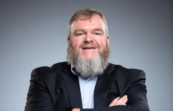 Business professional smiling and arms folded.