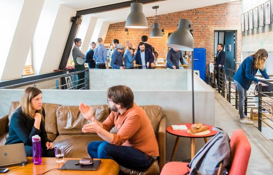 Modern workplace collaboration with employees engaging in feedback discussions and team interactions in a vibrant office setting.