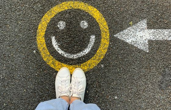 Smiley face and arrow on pavement symbolizing positive employee engagement direction and culture optimization