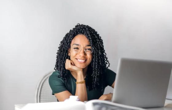 Smiling woman at desk with laptop, symbolizing employee engagement and feedback.