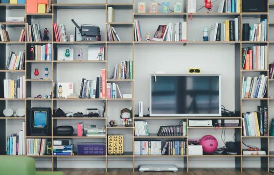 Modern bookshelf showcasing a blend of books, gadgets, and personal items, reflecting a creative organizational climate and an engaging company culture.