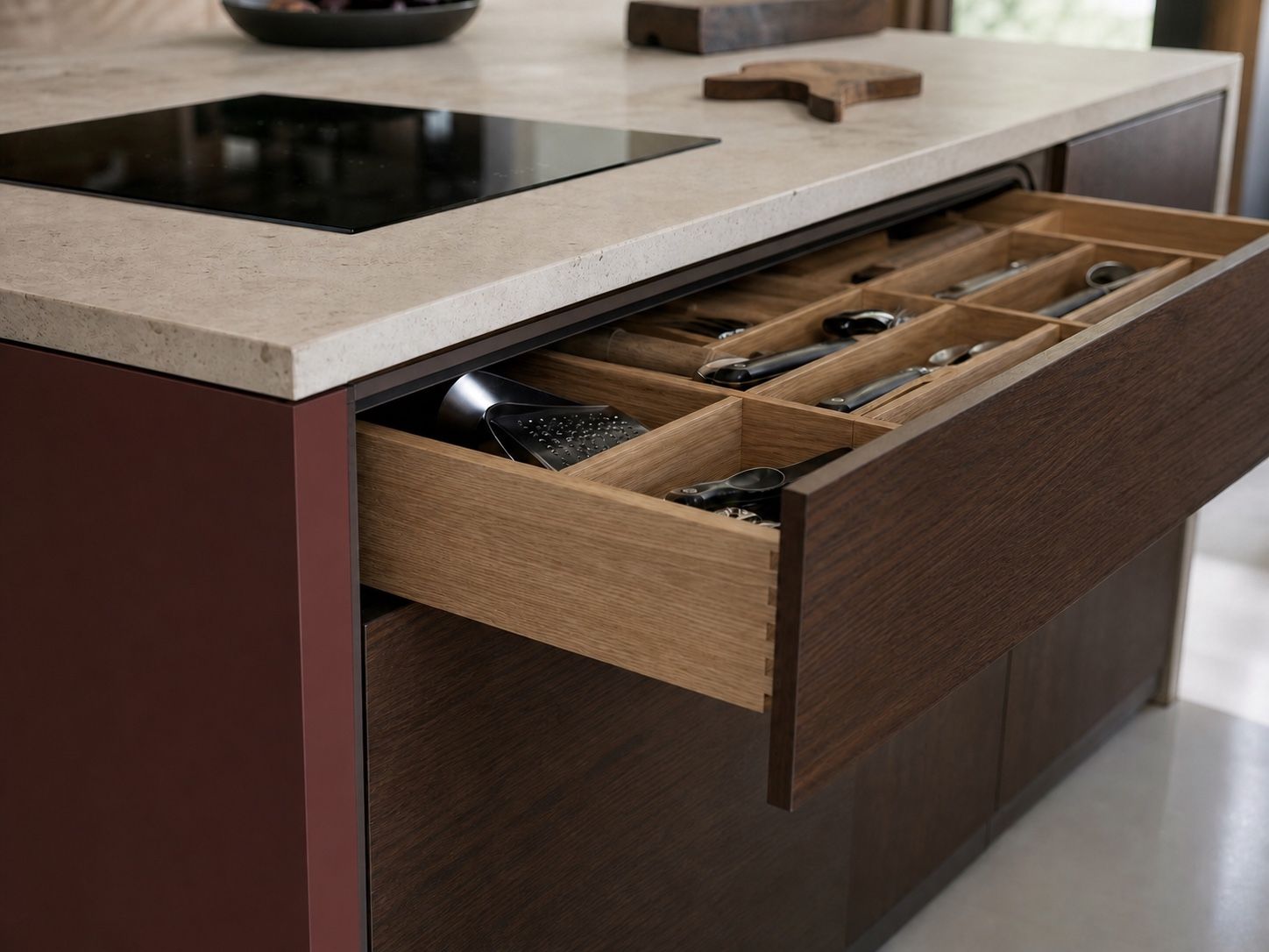 Open walnut kitchen island drawer with oak dividers and a pale limestone worktop