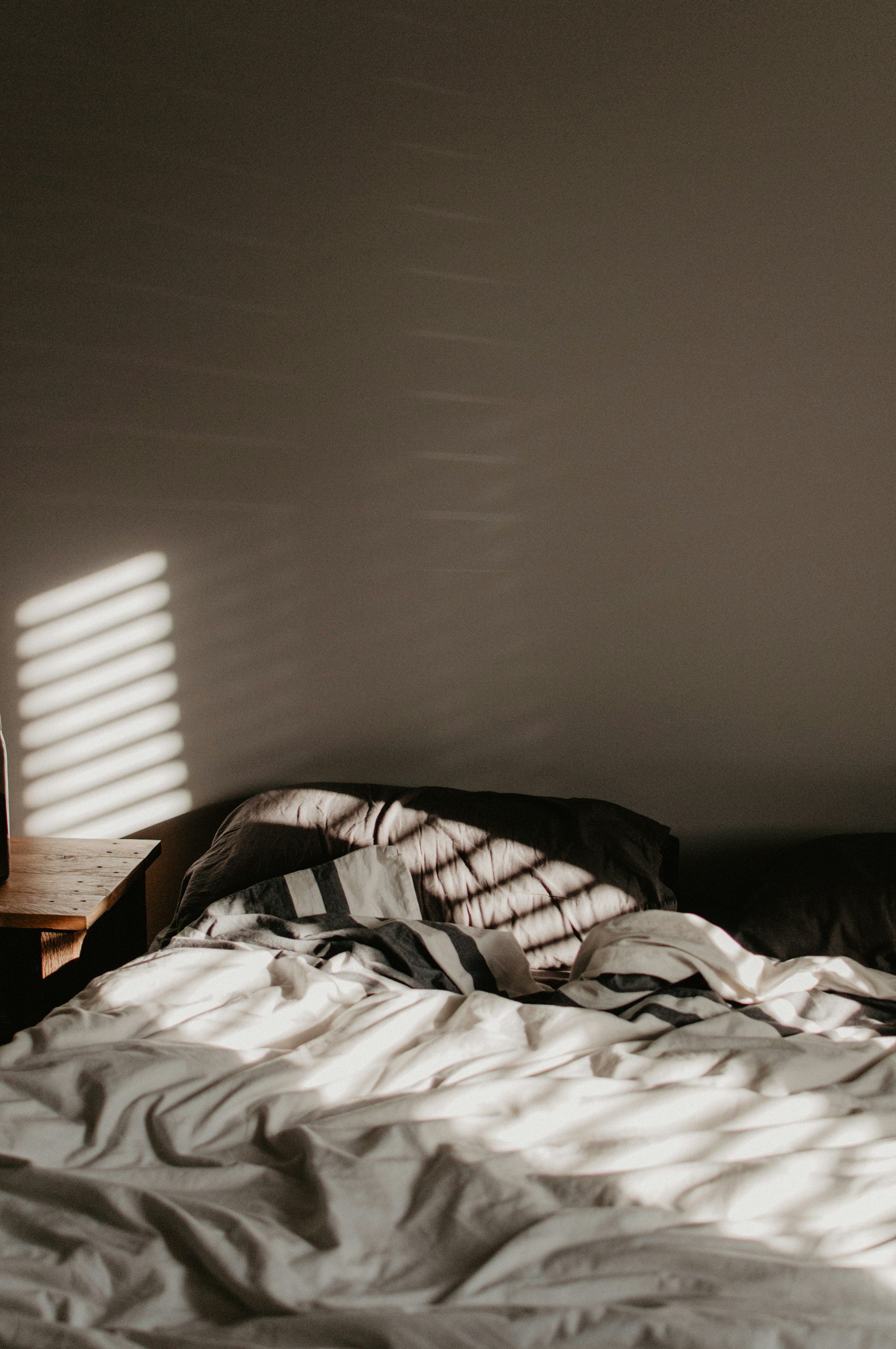 Soft evening light across a calm bed with striped bedding
