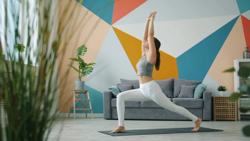 Woman practising a gentle yoga stretch on a mat in a bright living room