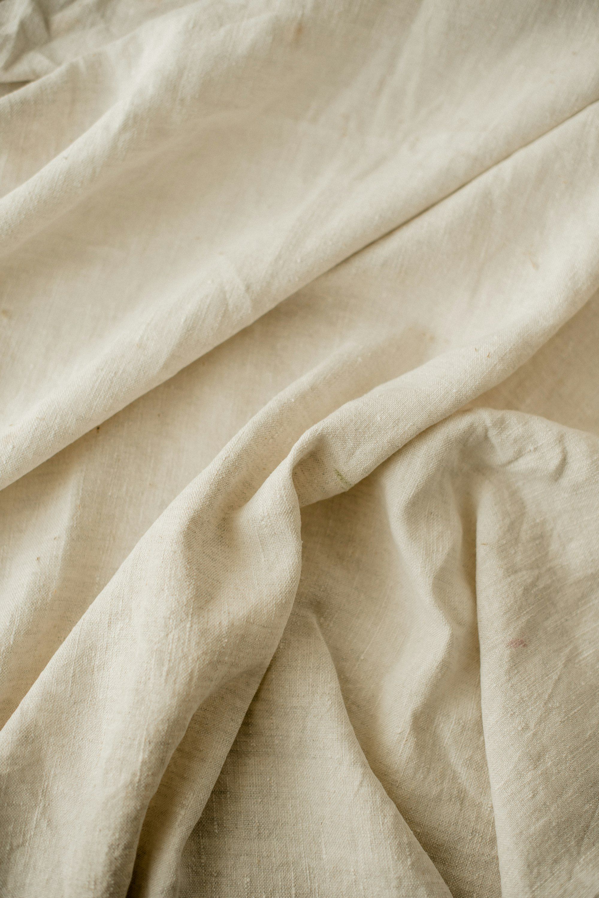 Close-up of soft folds in natural cream linen fabric