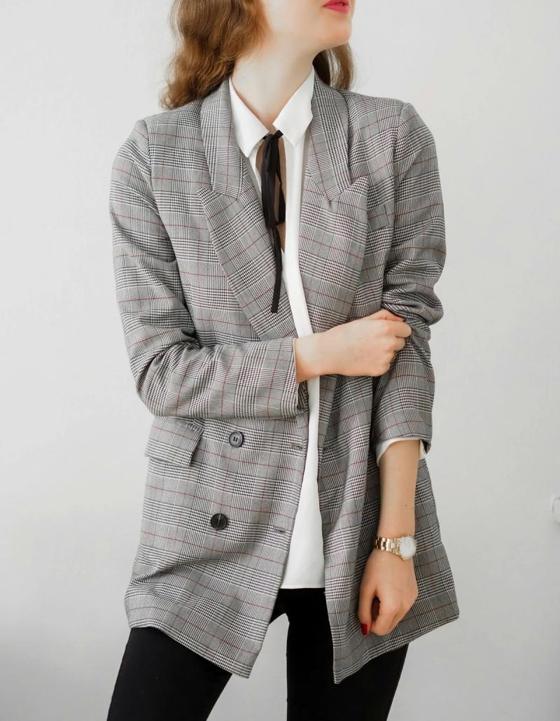 Woman in a grey checked blazer and black trousers