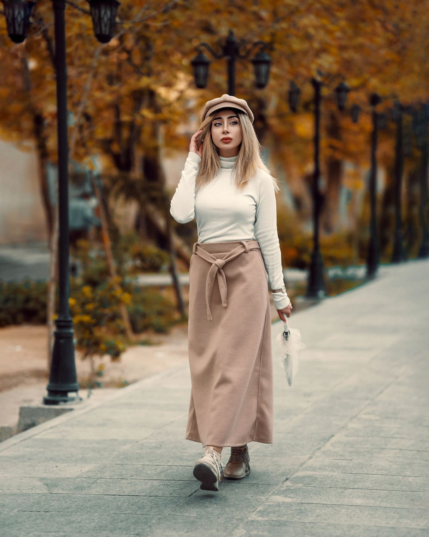 Woman walking down an autumn street in a cream knit and long skirt