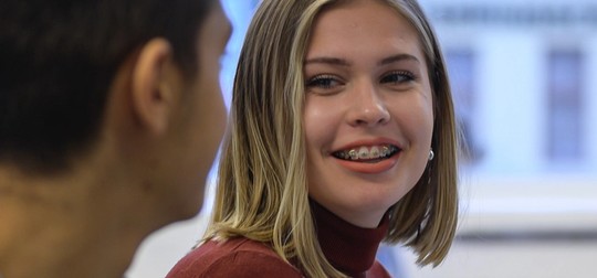 Tjej med tandställning pratar med klasskompis