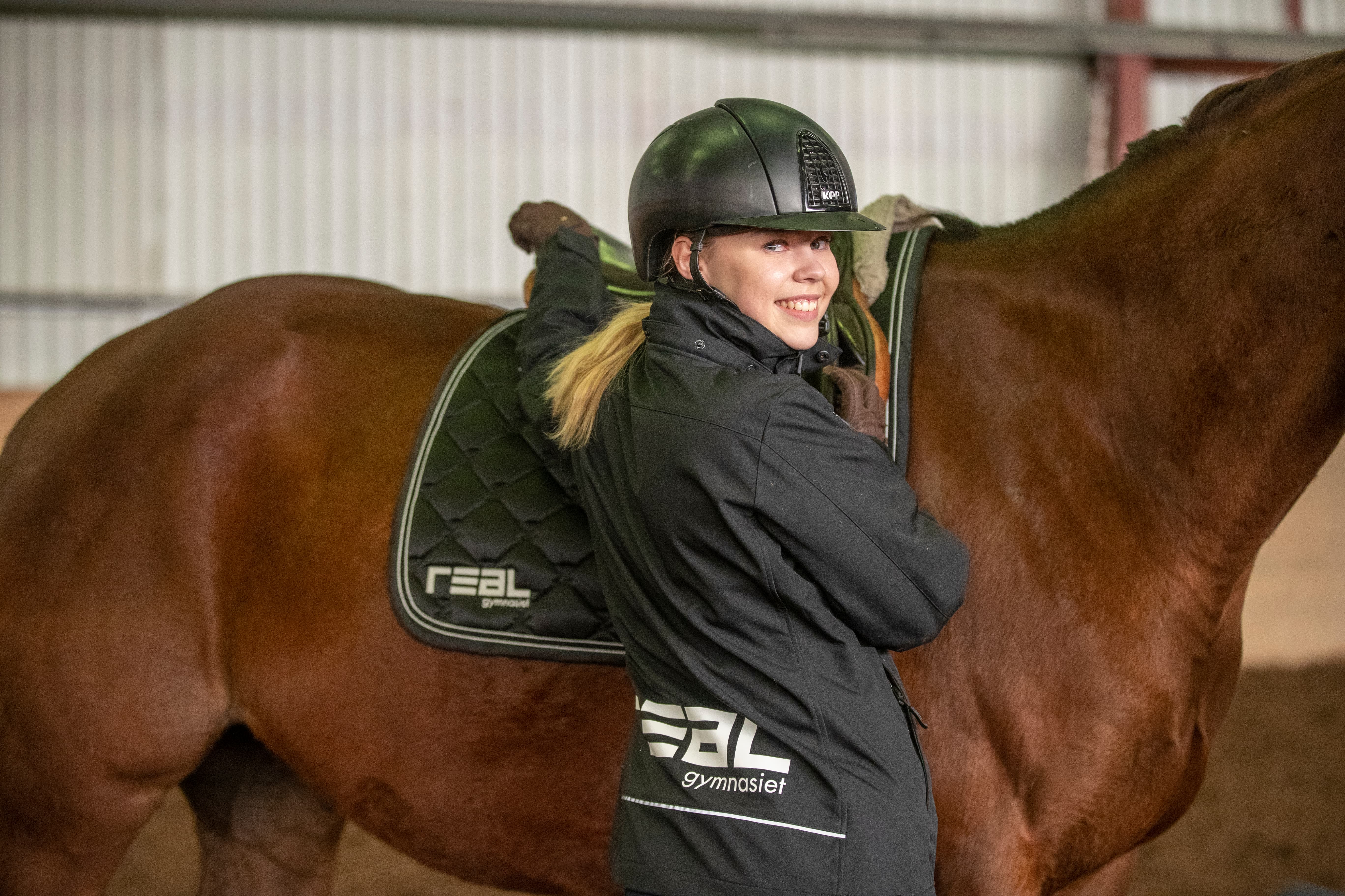 tjej som står framför brun häst