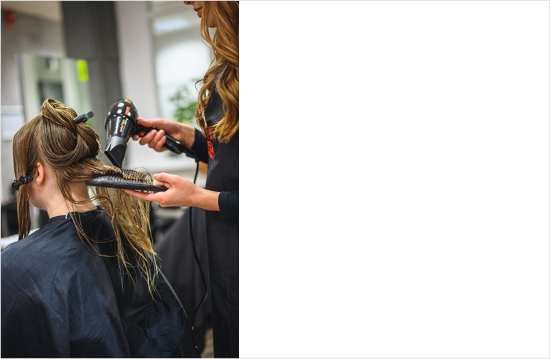 Frisörelev fönar hår på kund