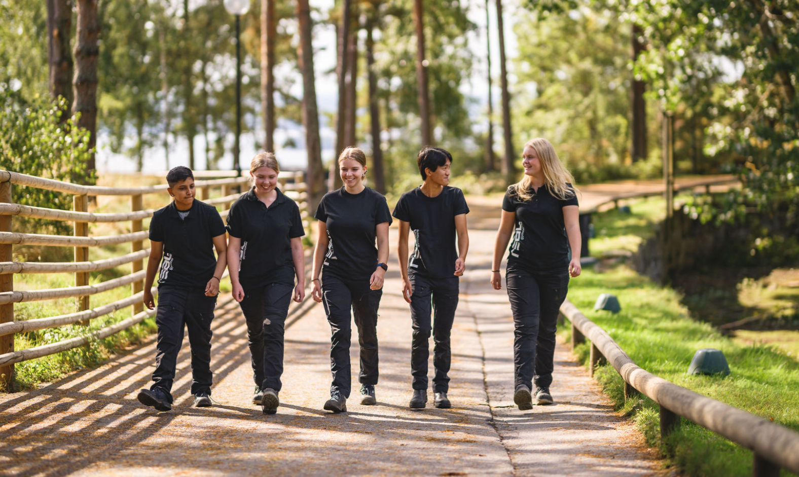 Två elever står bredvid varandra i ett uppehållsrum på skolan och ler glatt mot kameran.
