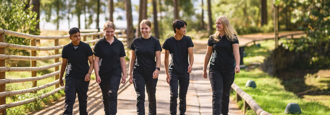 Två elever står bredvid varandra i ett uppehållsrum på skolan och ler glatt mot kameran.