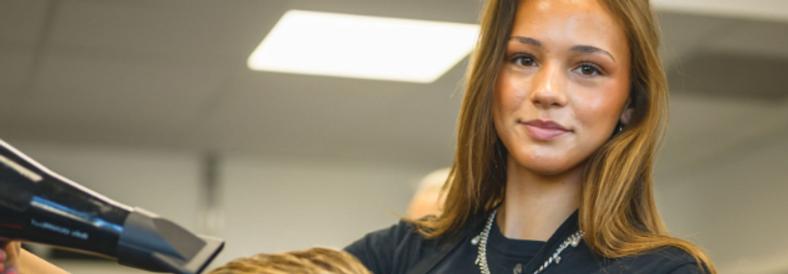 Elev fönar hår på kund