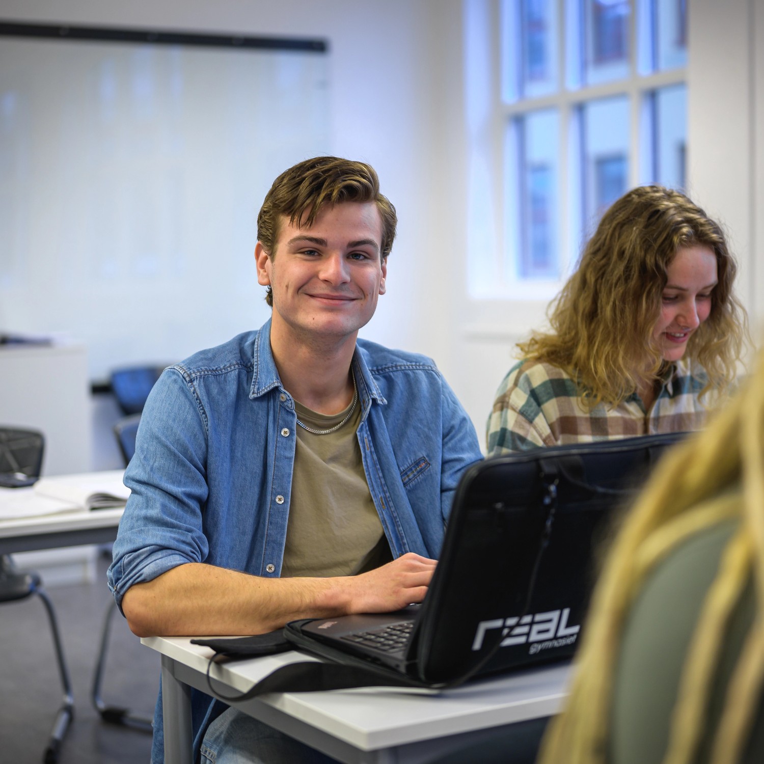 manlig elev i klassrum, vid laptop