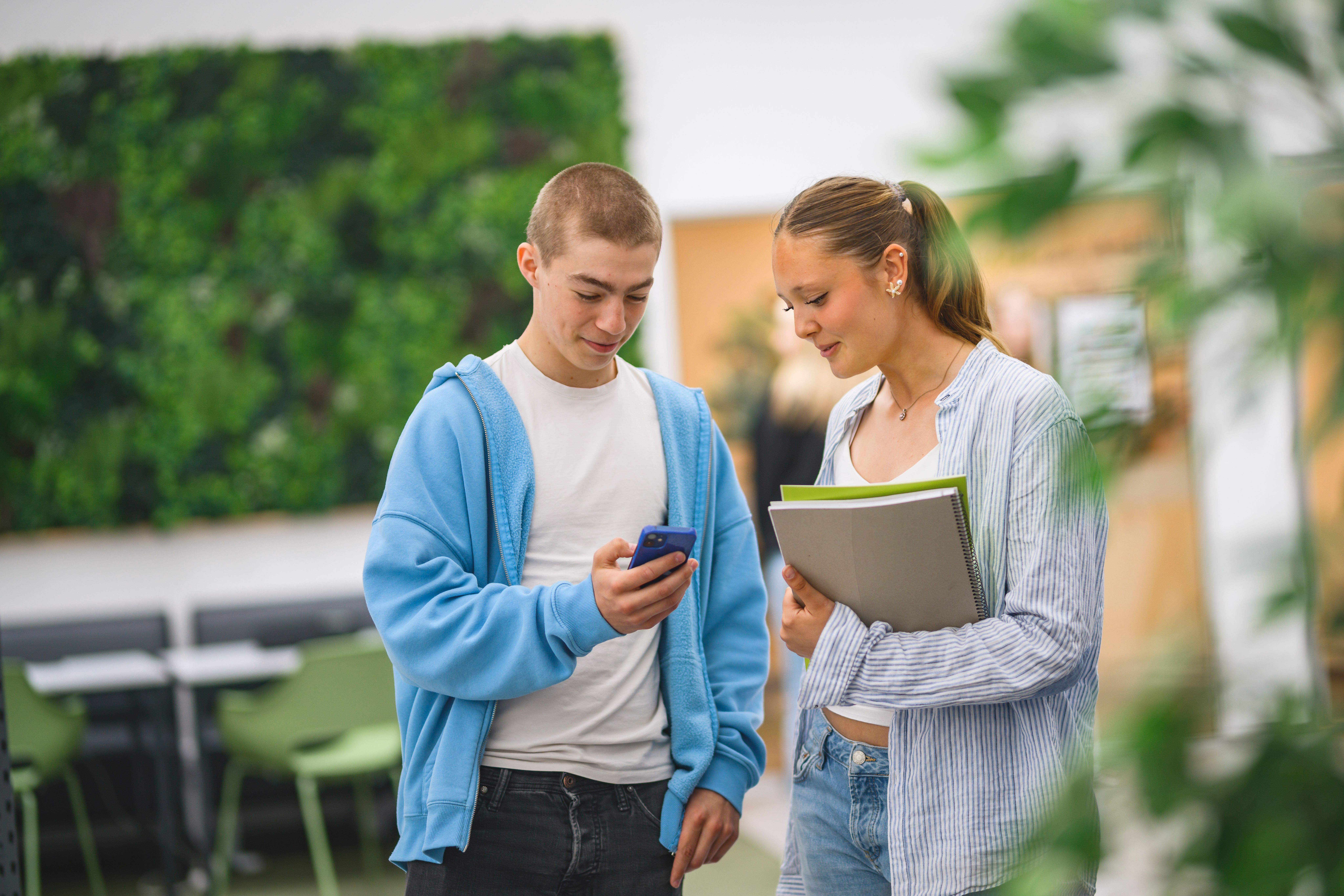 Elev med mobiltelefon i handen bredvid klasskompis