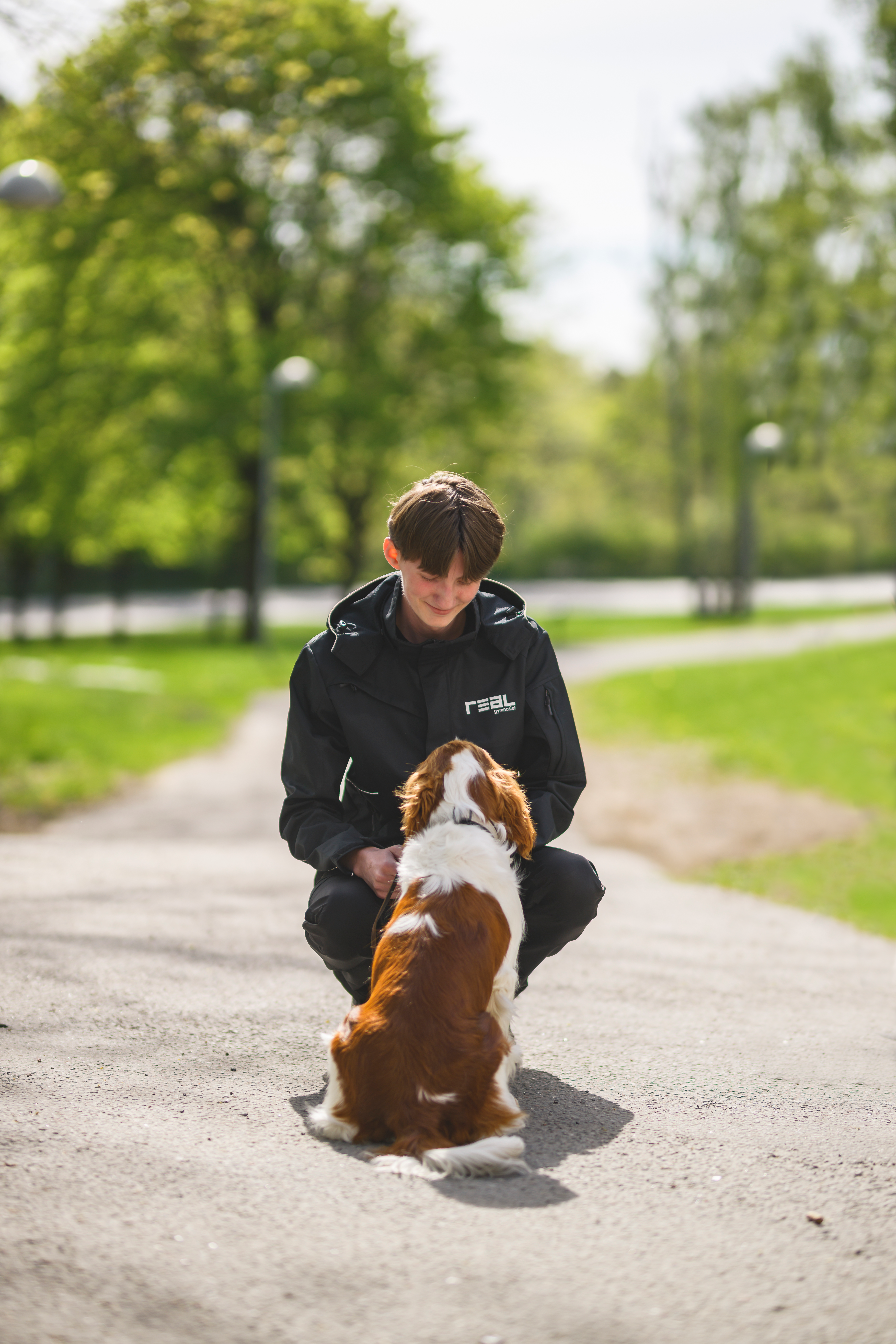 elev på huk med en hund framför sig