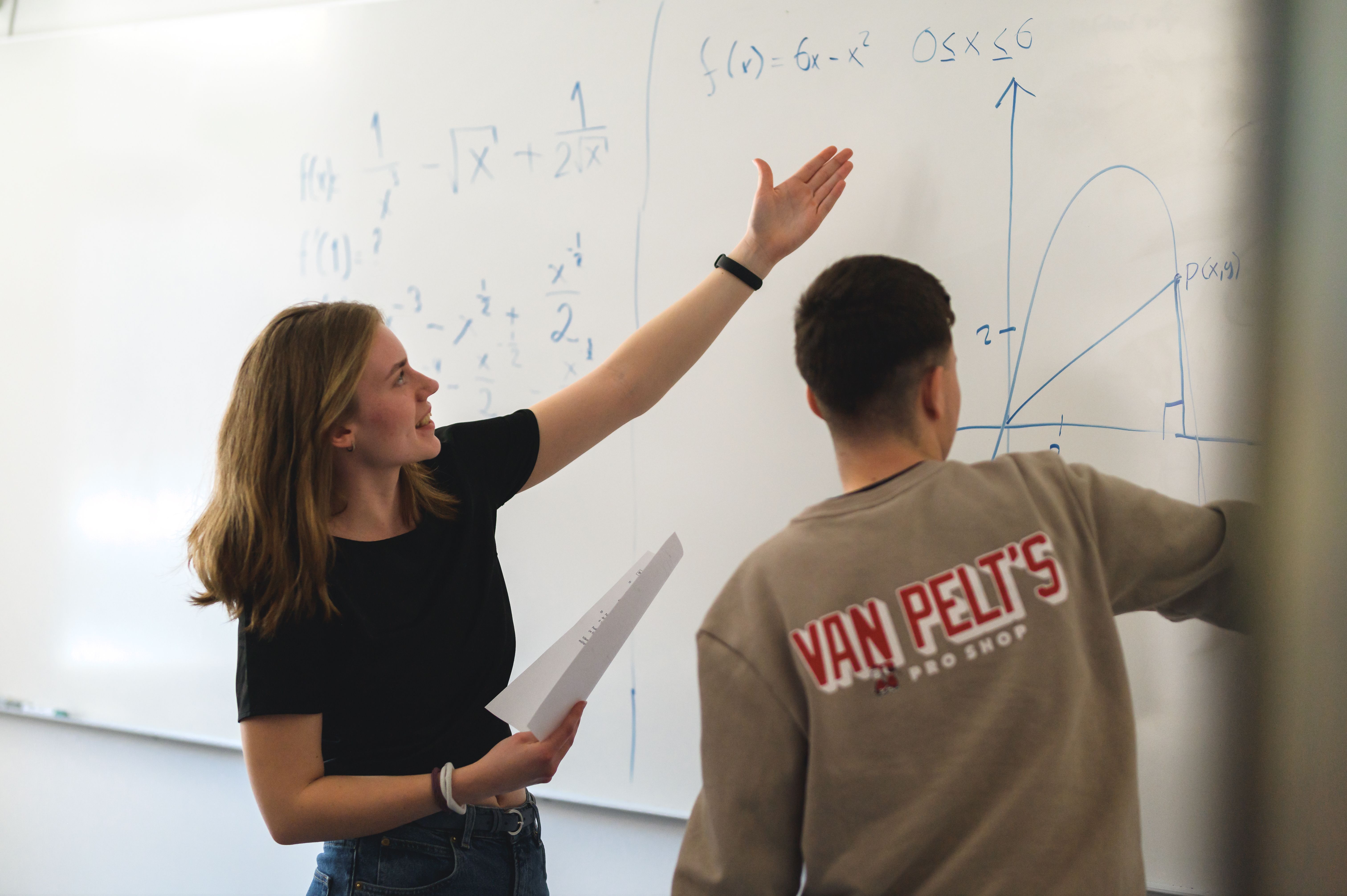 Två elever löser formler på whiteboard-tavla
