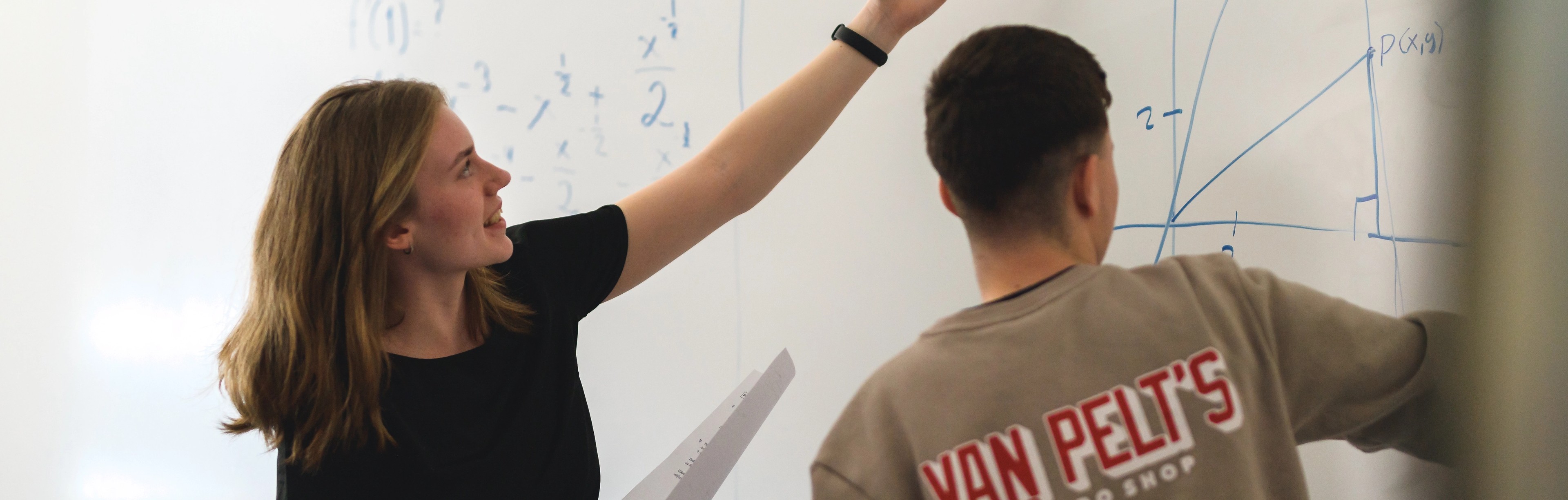 Två elever löser formler på whiteboard-tavla