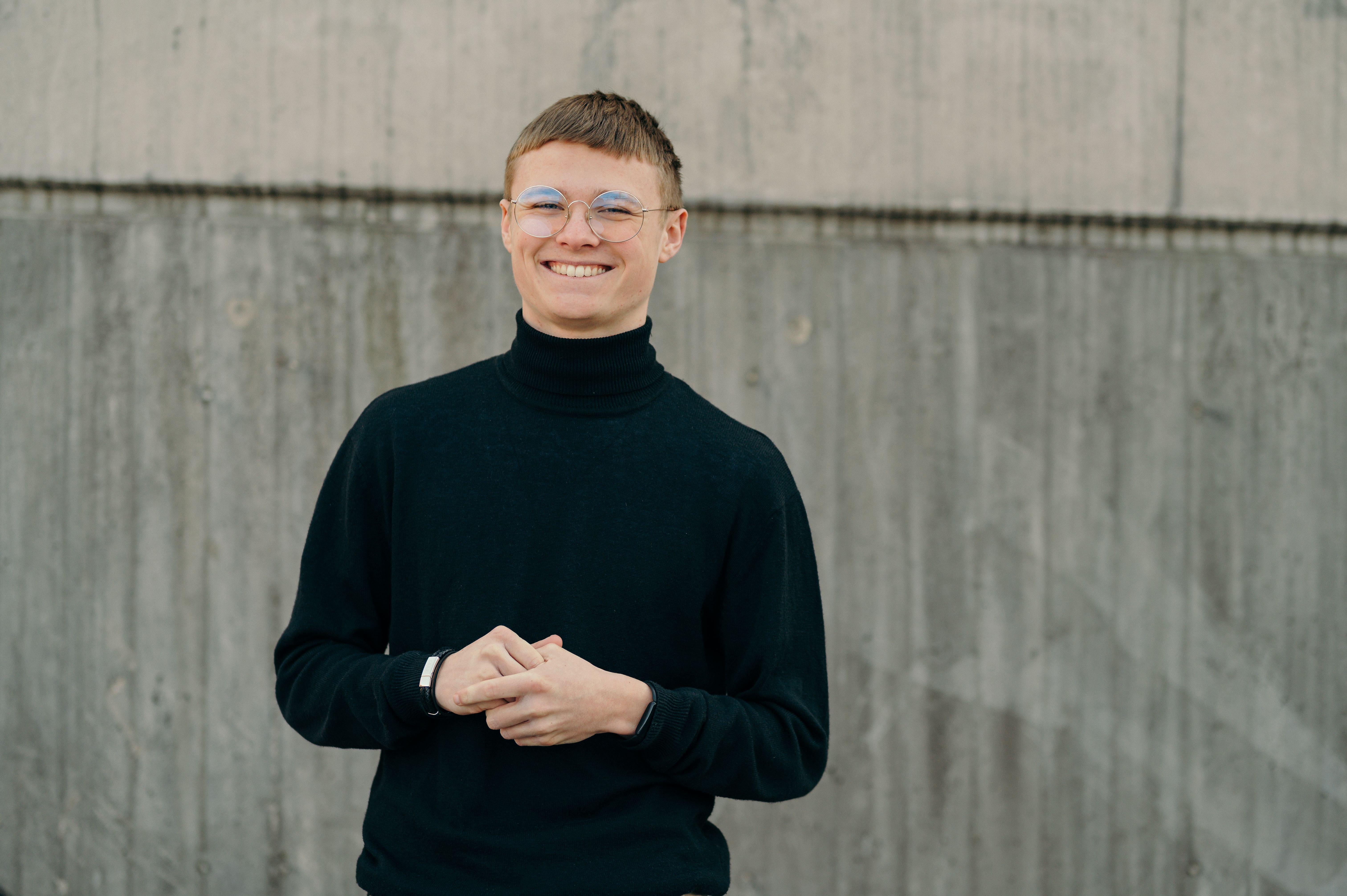 Kille som ler in i kameran framför vägg