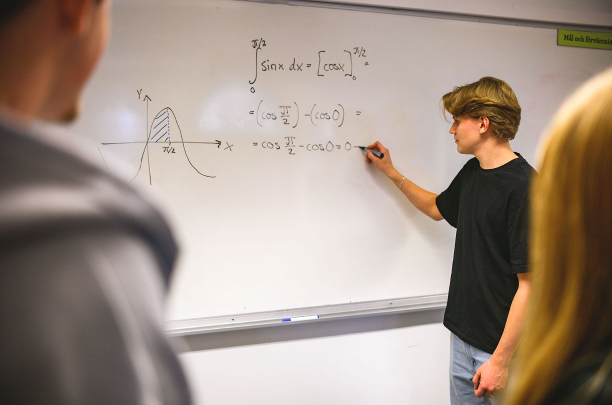 En elev skriver en matematisk formel på en whiteboard