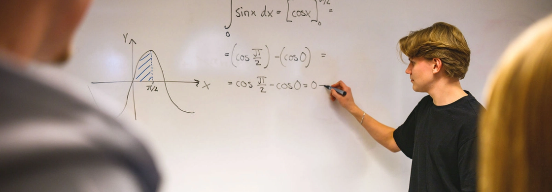 En elev skriver en matematisk formel på en whiteboard