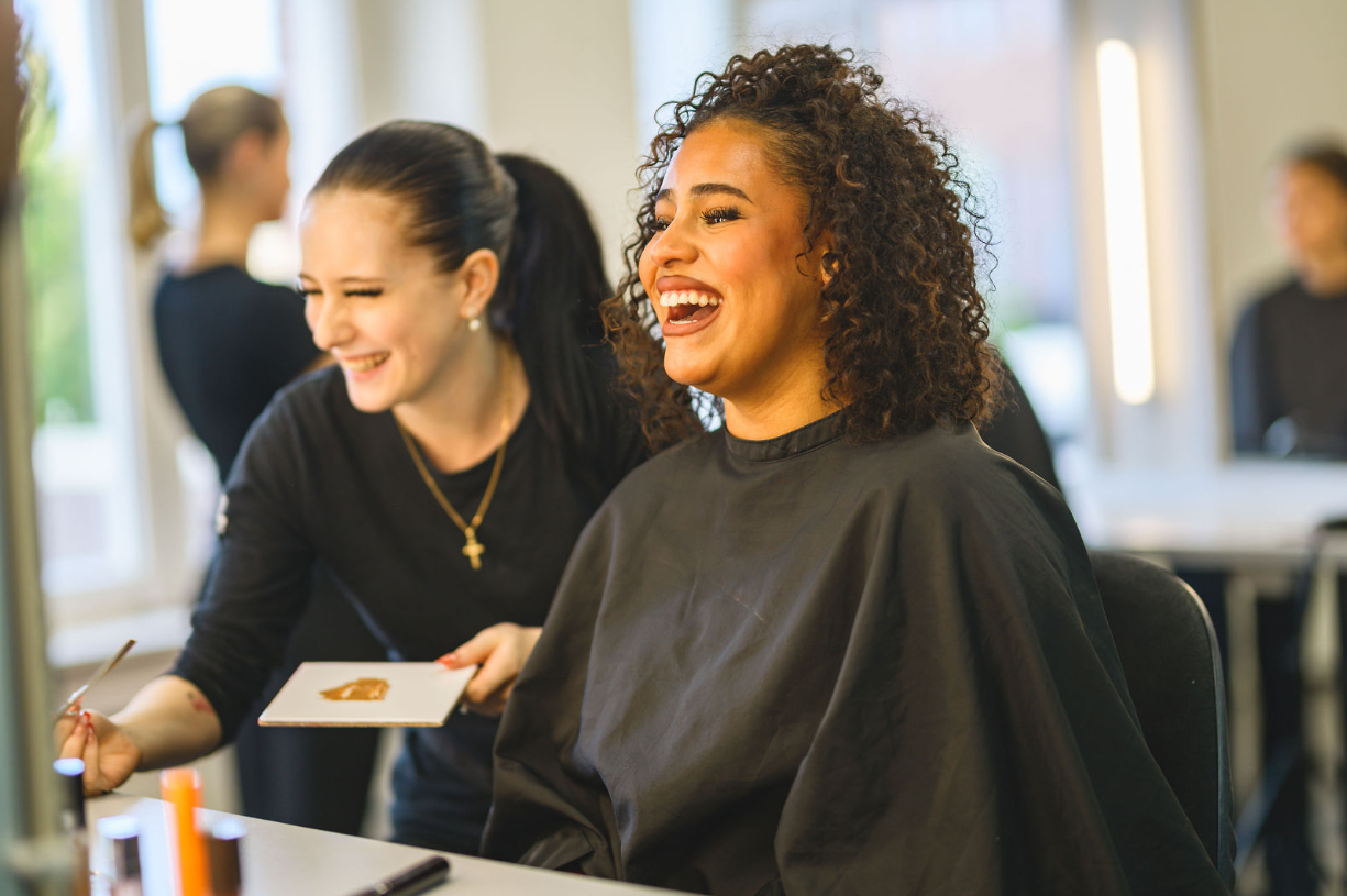 en elev som sminkar modell framför spegel