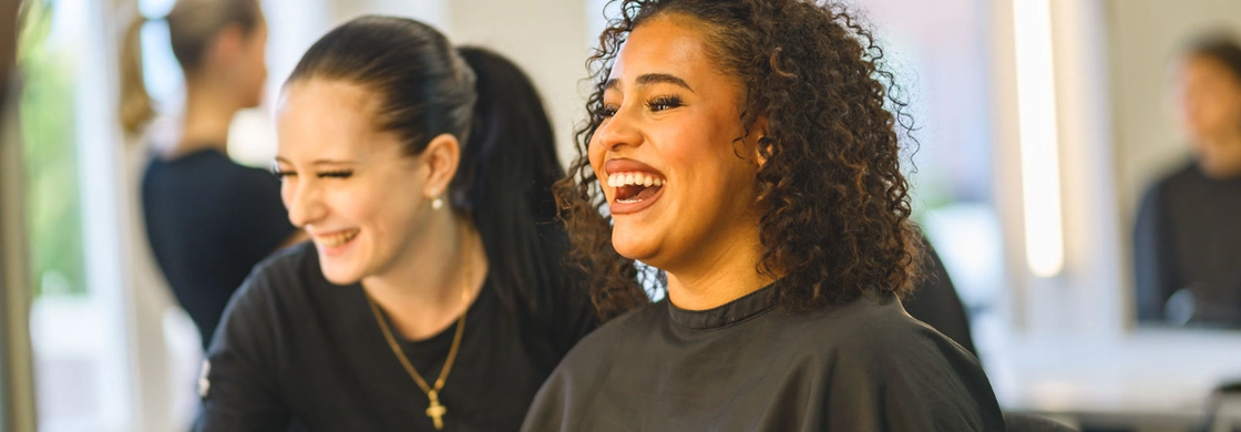 en elev som sminkar modell framför spegel