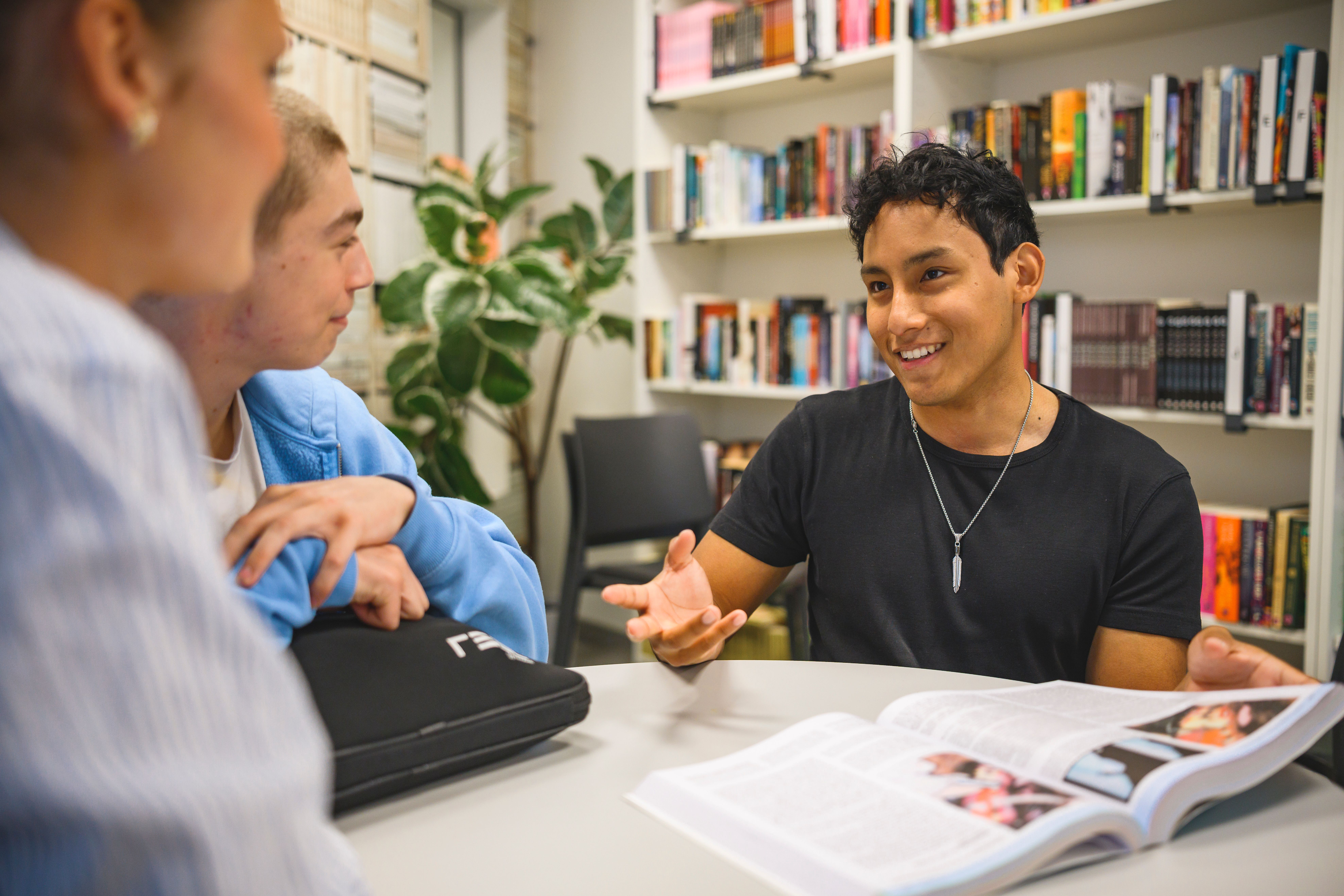 Elever samtalar runt en bok i biblioteket