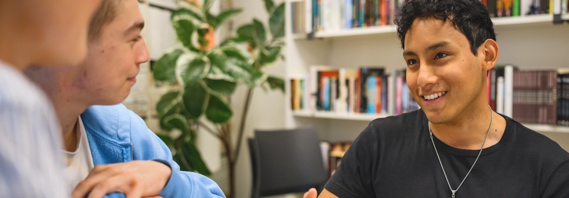 Elever samtalar runt en bok i biblioteket