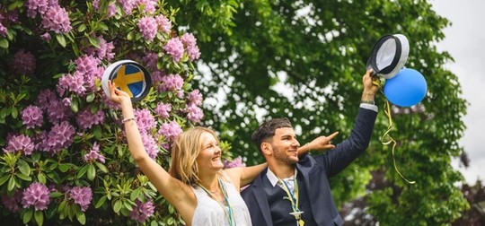 Tjej och kille som viftar med studentmössor