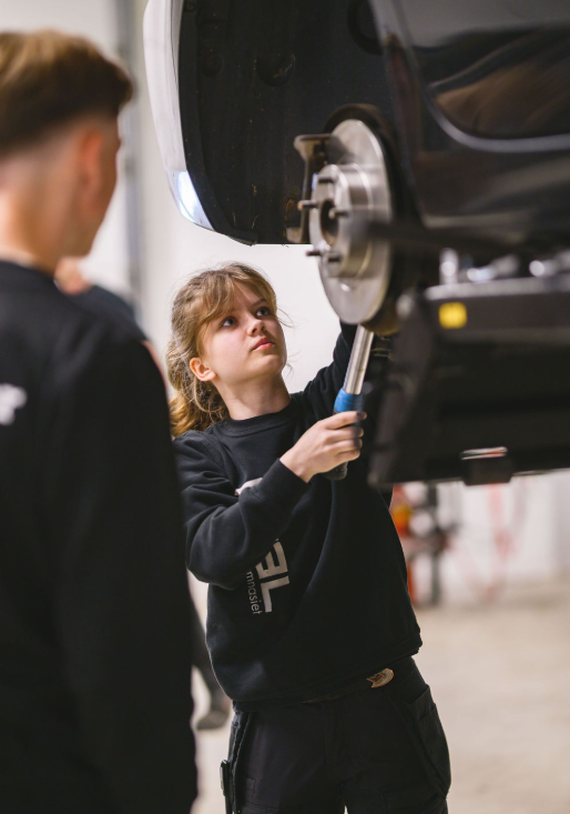 Elev skruvar under en bil