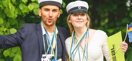 Kille och tjej som är glada i studentkläder