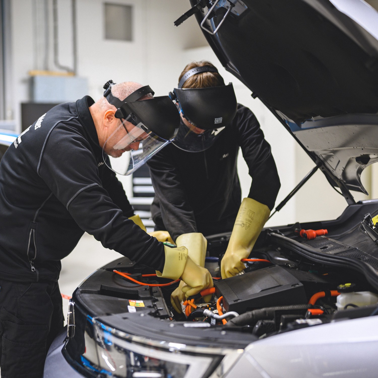 Elev med handledare arbetar i motorn på bil i Promeisters verkstad.